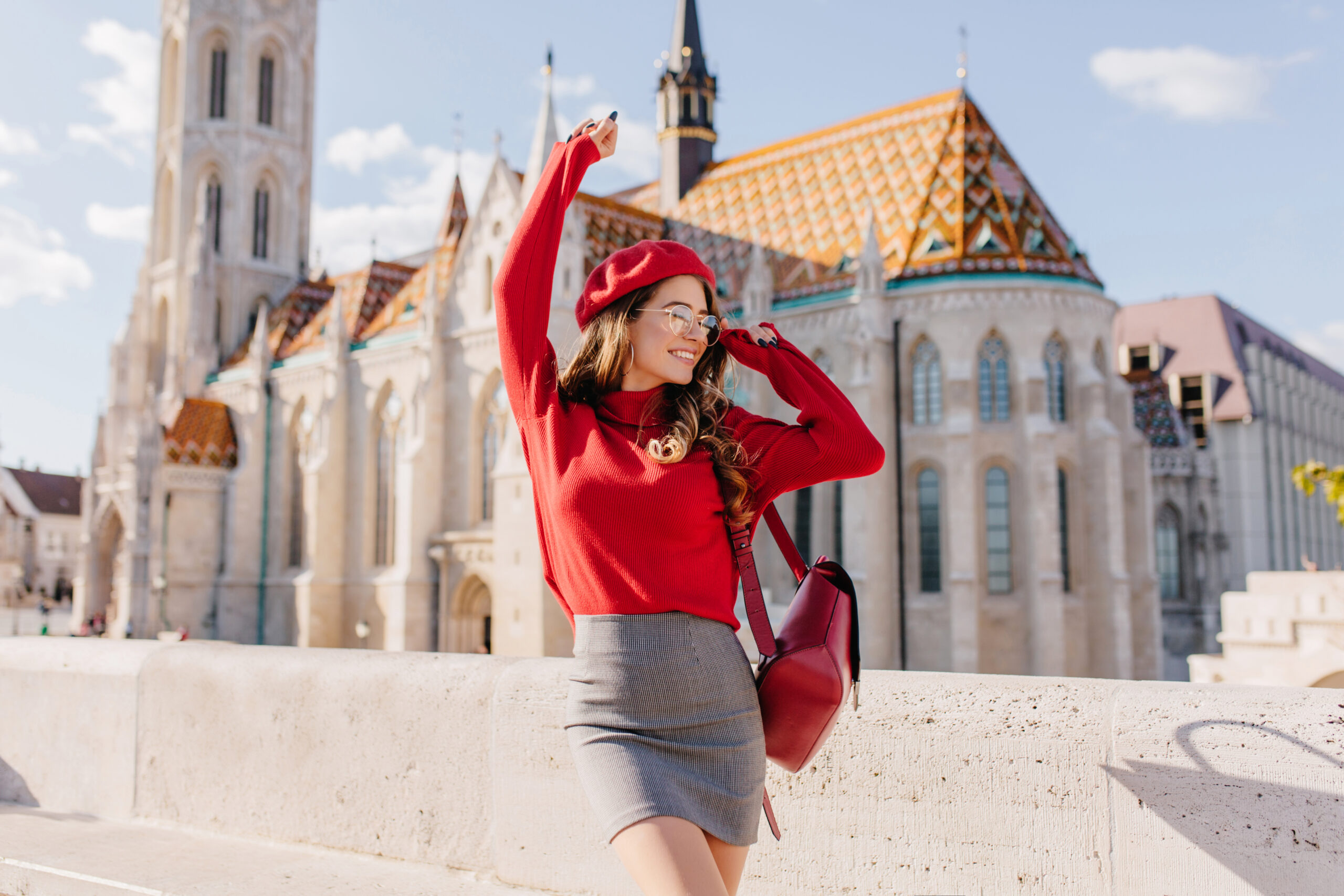 winsome girl in gray skirt dancing with happy face expression with palace on background. outdoor portrait of lovely lady posing in front of old beautiful building..