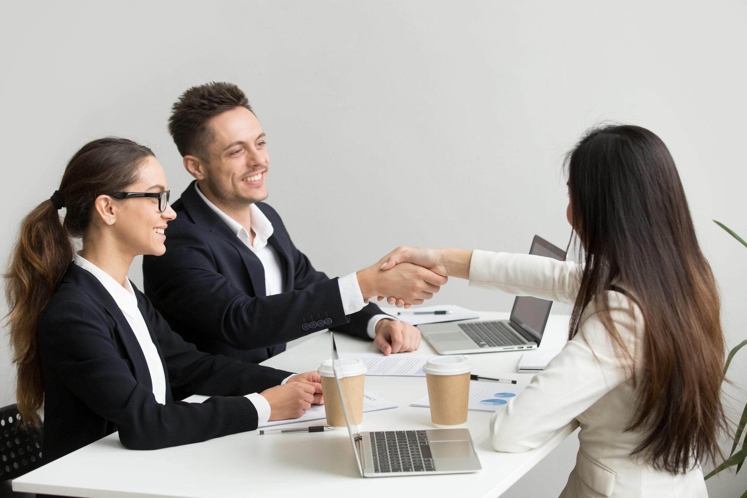 friendly partners handshaking at group meeting thanking for succ